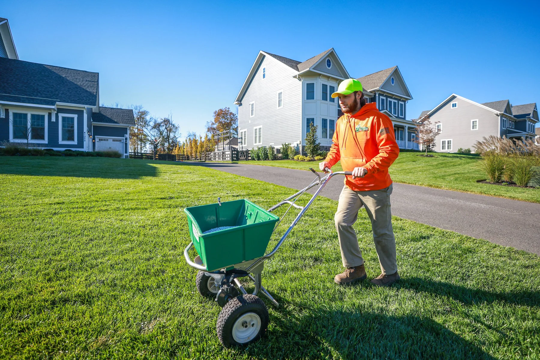 lawn care technician spreading granular fertilizer