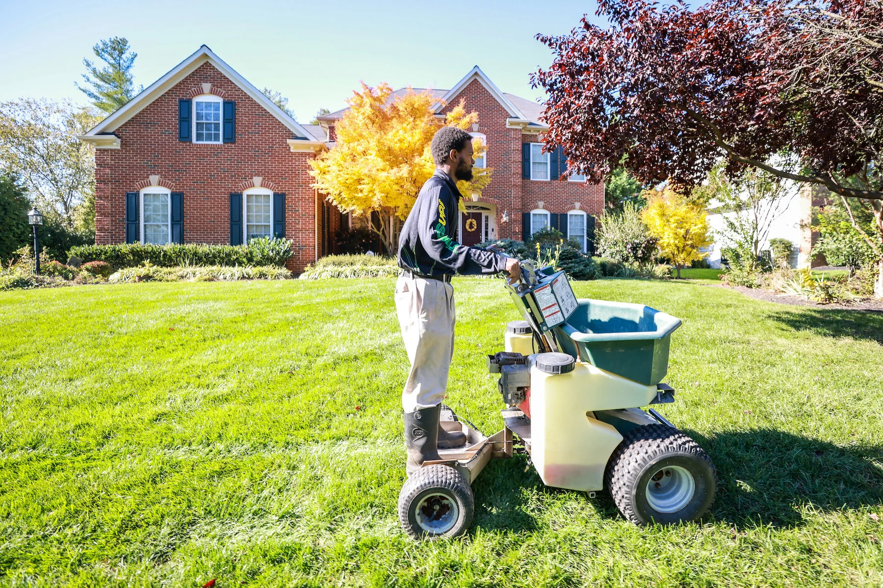 lawn care technician fertilizes lawn with liquid fertilizer