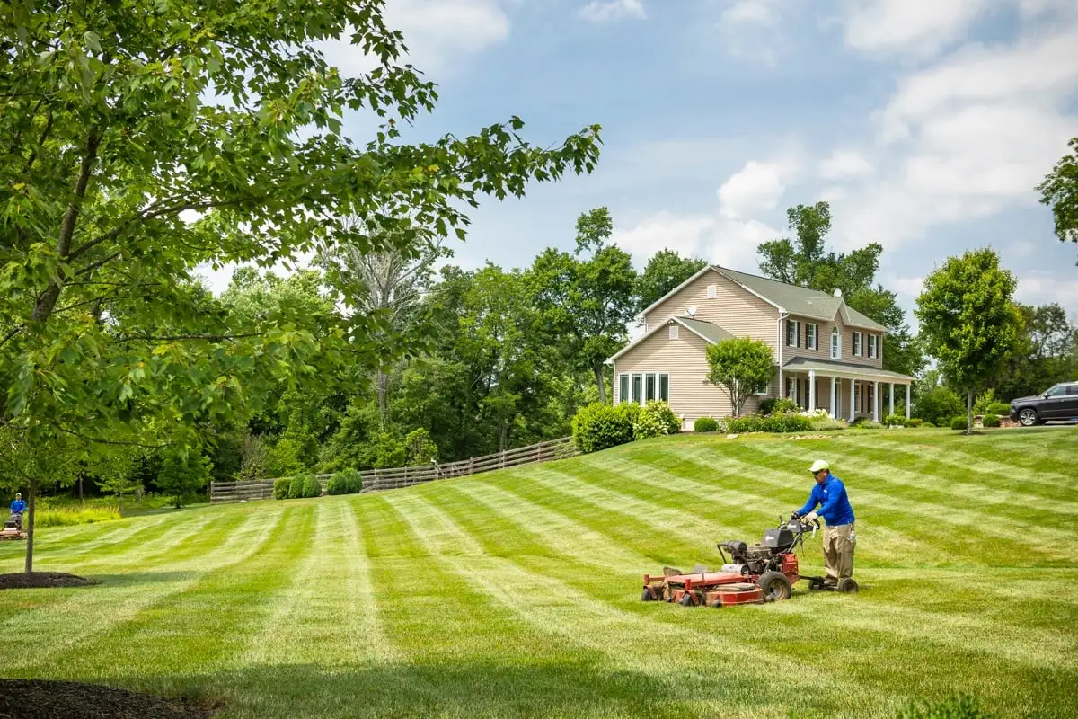 lawn maintenance crew mows lawn with ride-on lawn mower