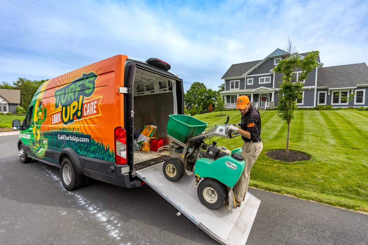 lawn care team pulls ride on fertilizer out of van