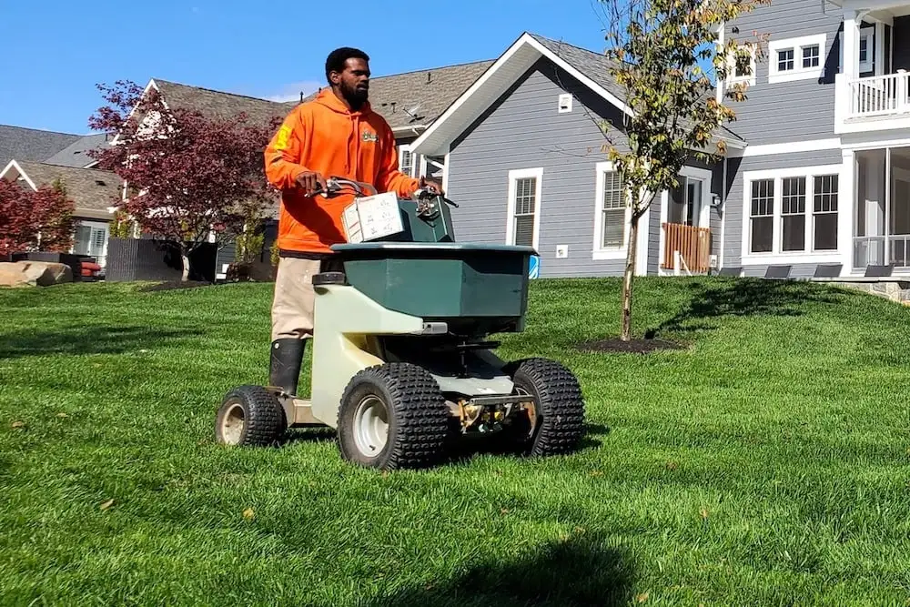 lawn care technician spreading fertilizer